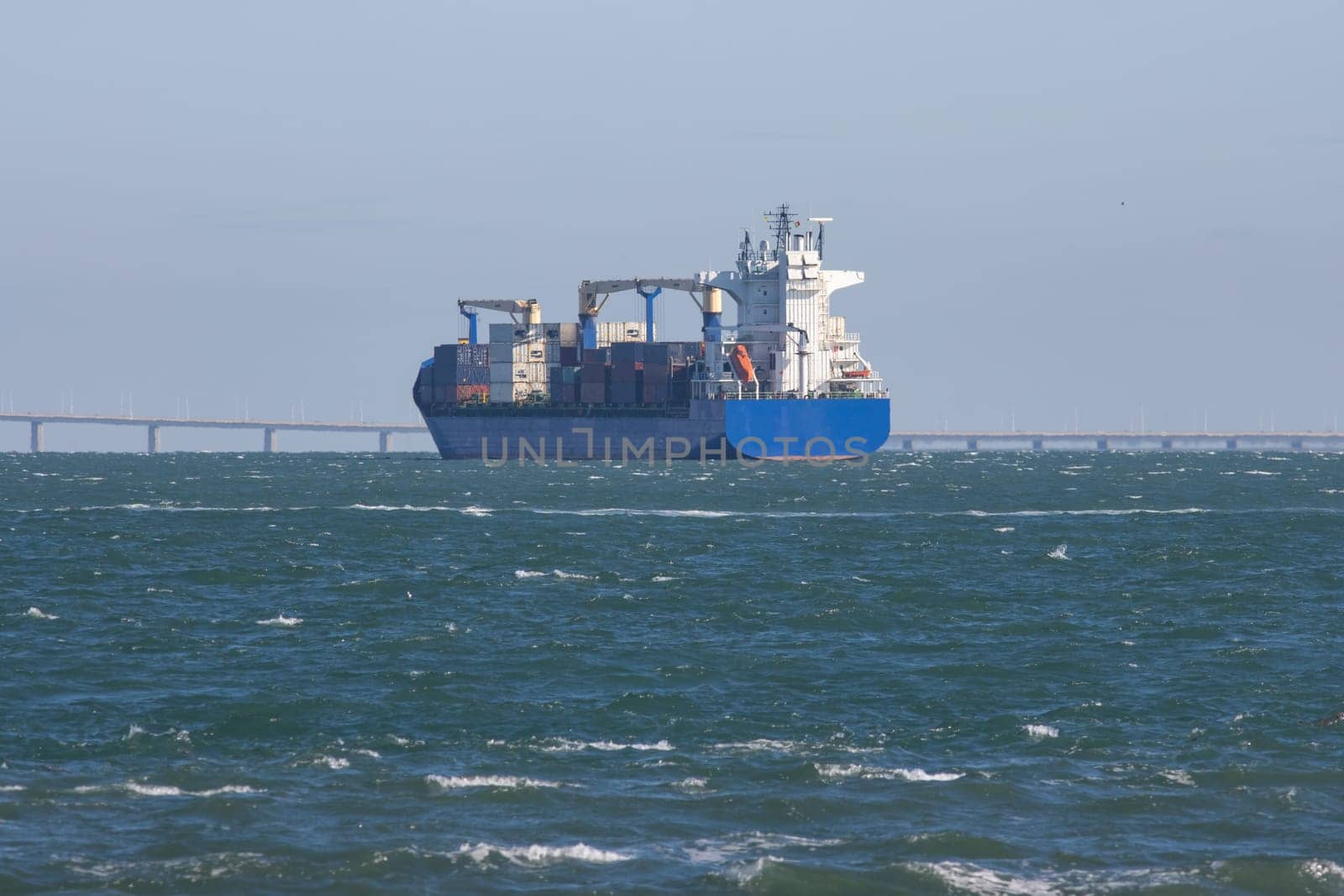 A big cargo ship sails the sea to the bridge. Mid shot