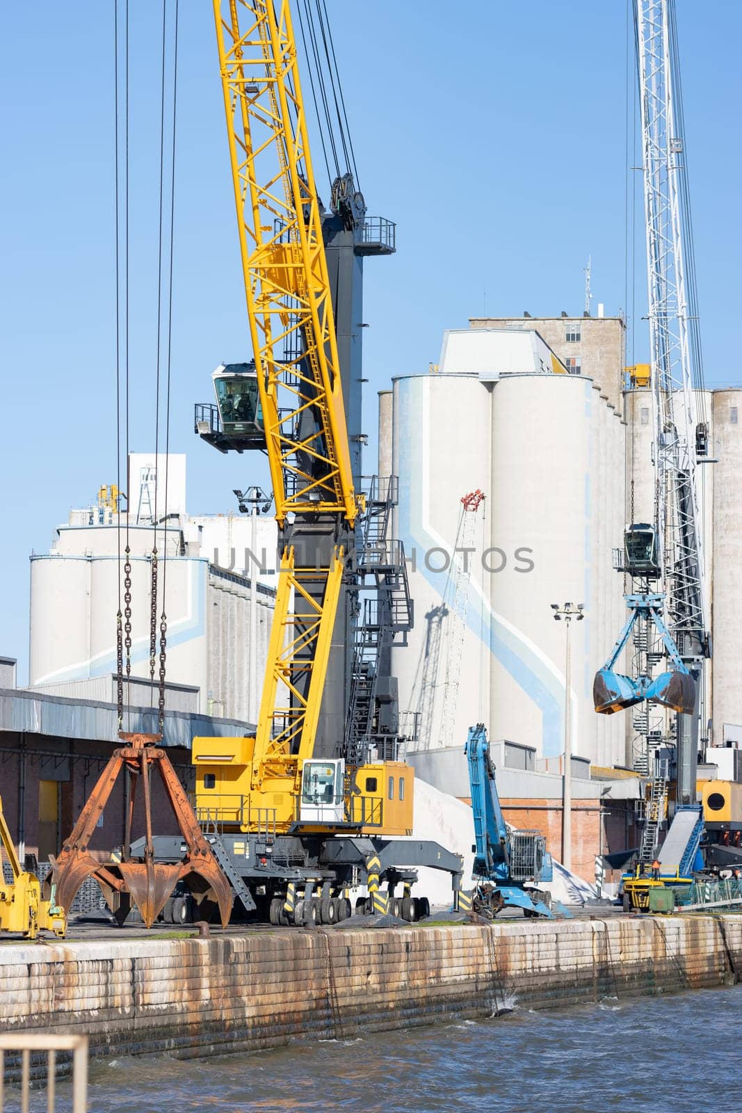 Cargo cranes operate in the seaport. Vertical shot
