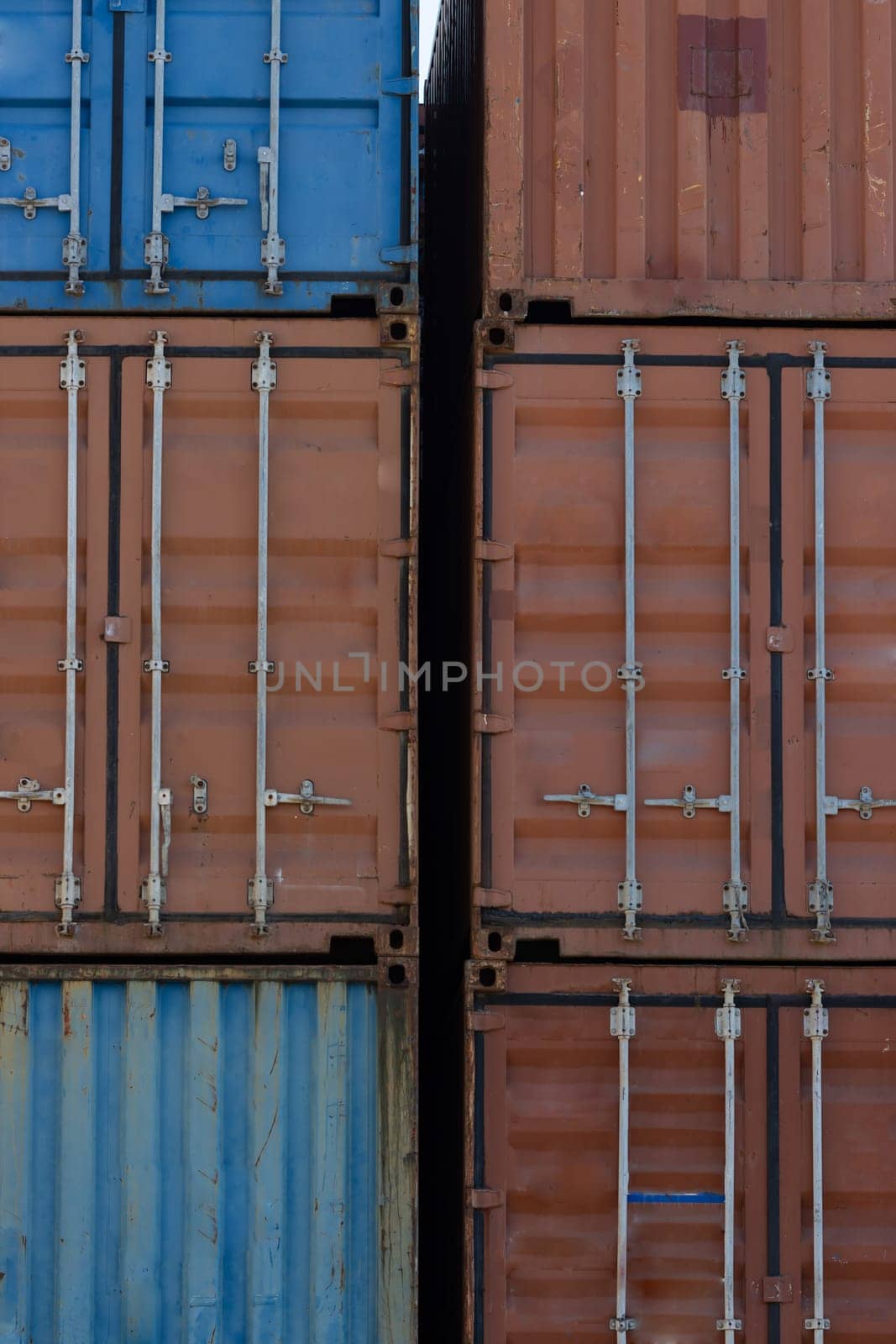 Closed doors of multicolored cargo containers in the port. Vertical shot
