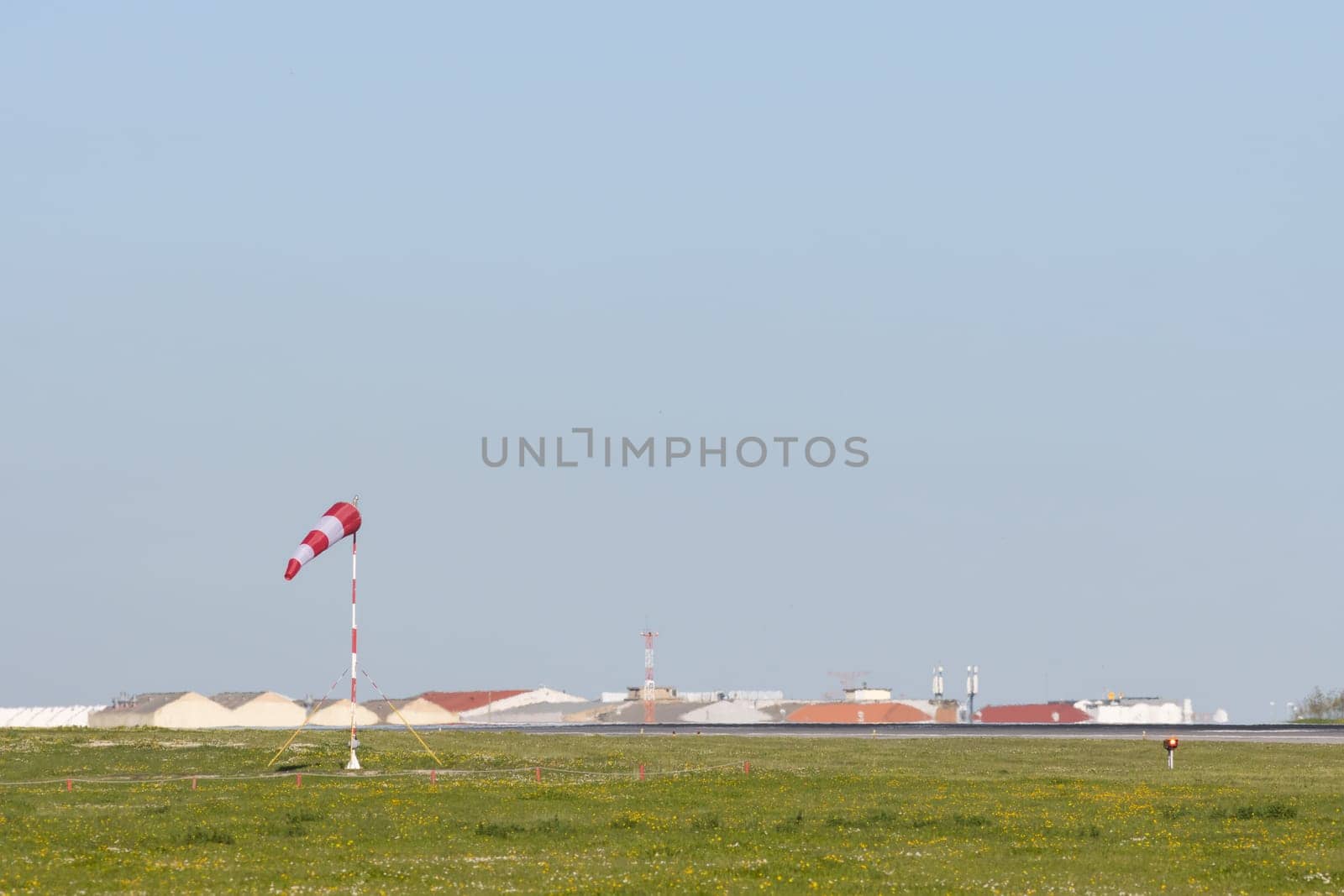 A green field and a warning sign in the middle of it - blurred warehouses in the background. Mid shot