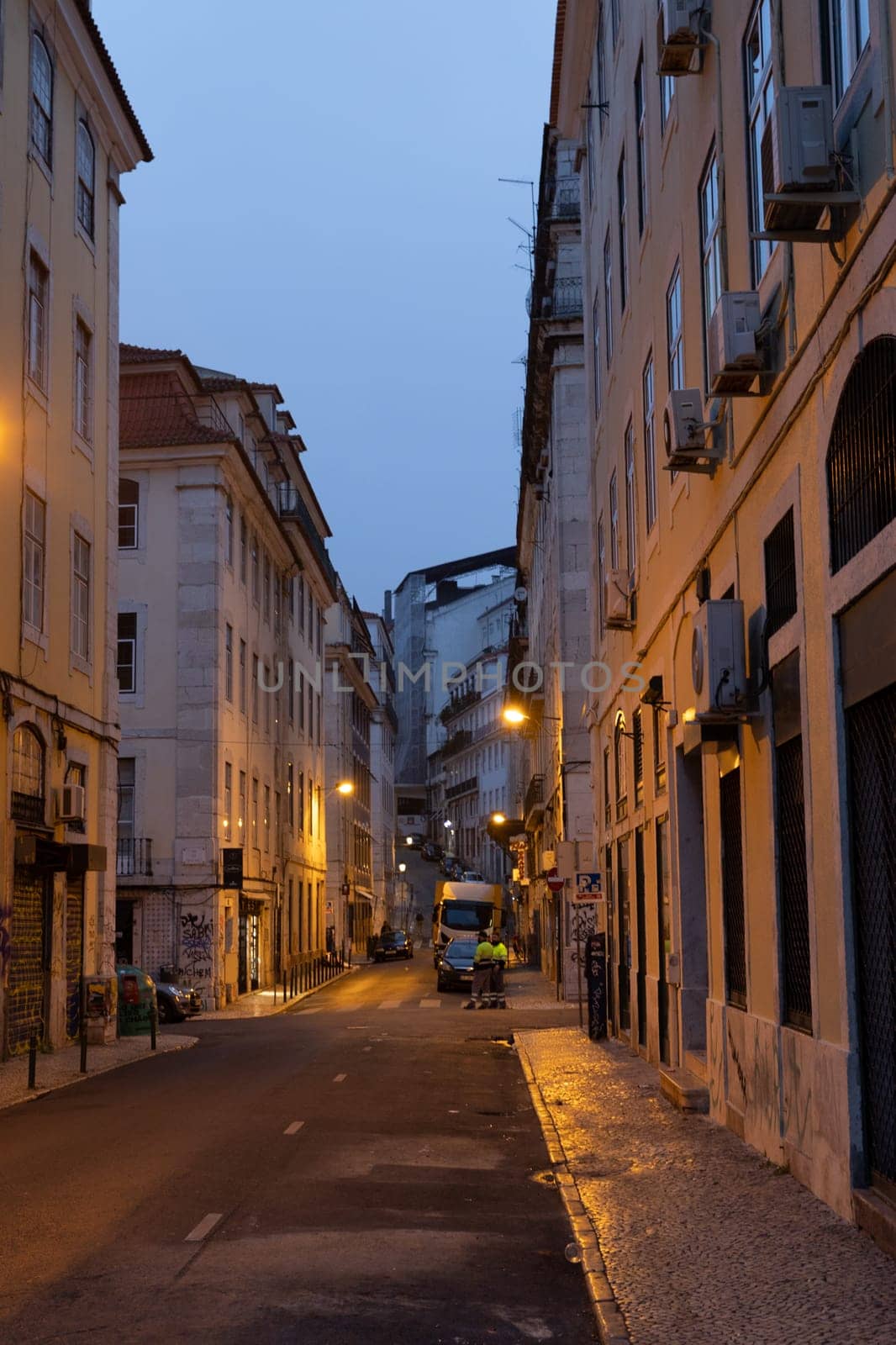 PORTUGAL, LISBON 12 december 2022: a European street and a couple of people in reflective vests in the early morning. Mid shot