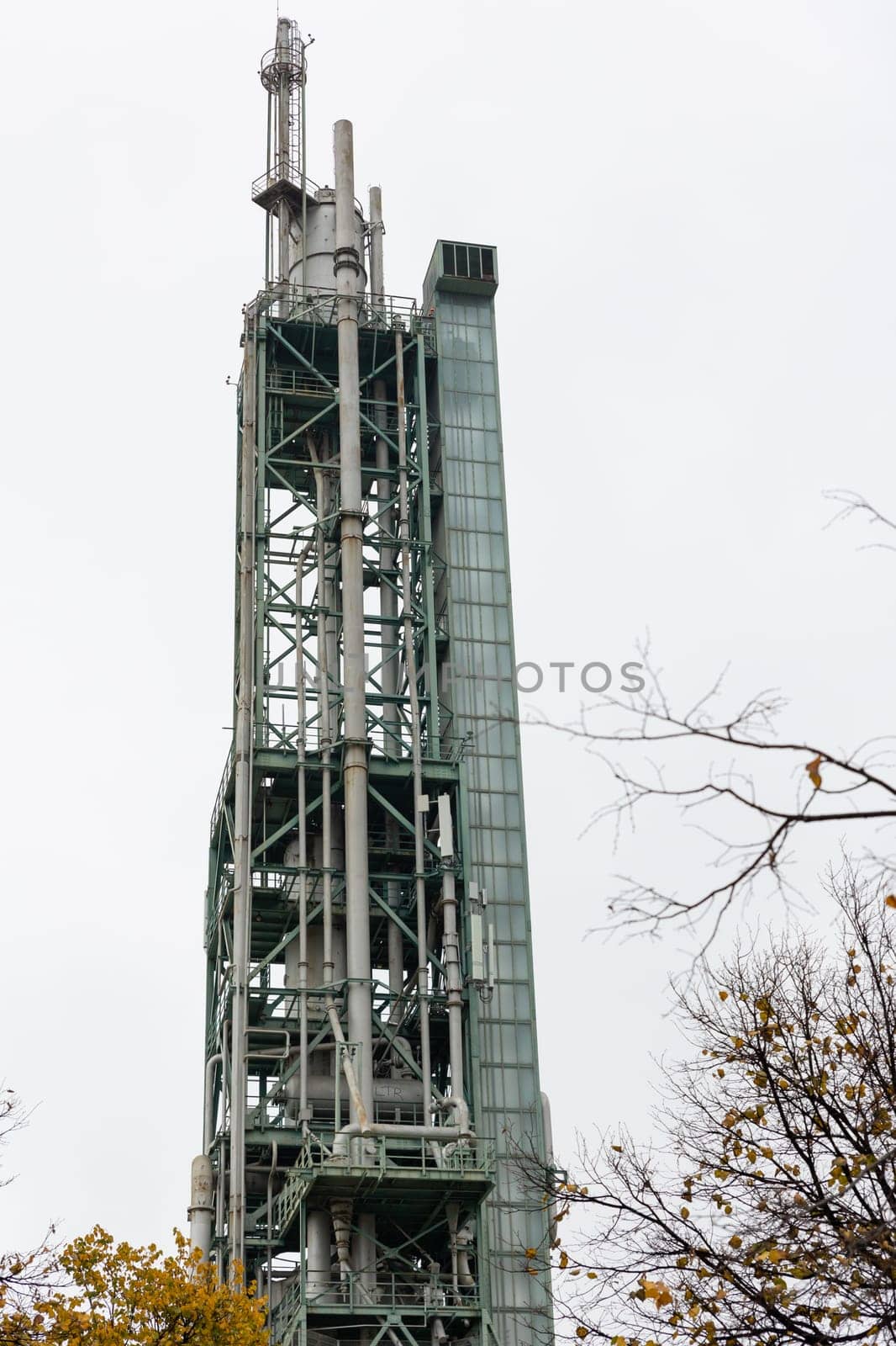 Oil and gas processing tower on a background of grey sky. Vertical shot