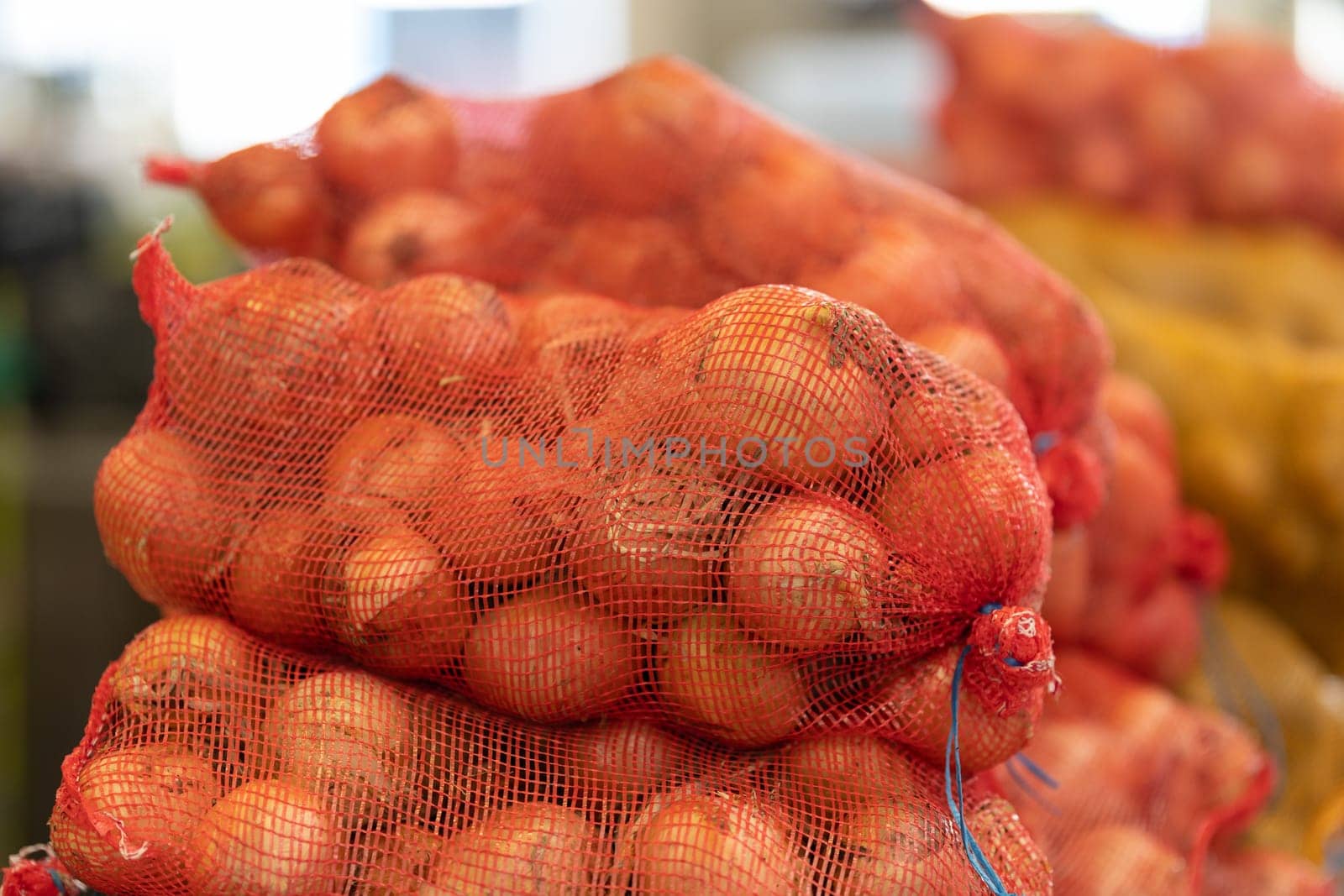 Kilograms of onions in a net at the market. Mid shot
