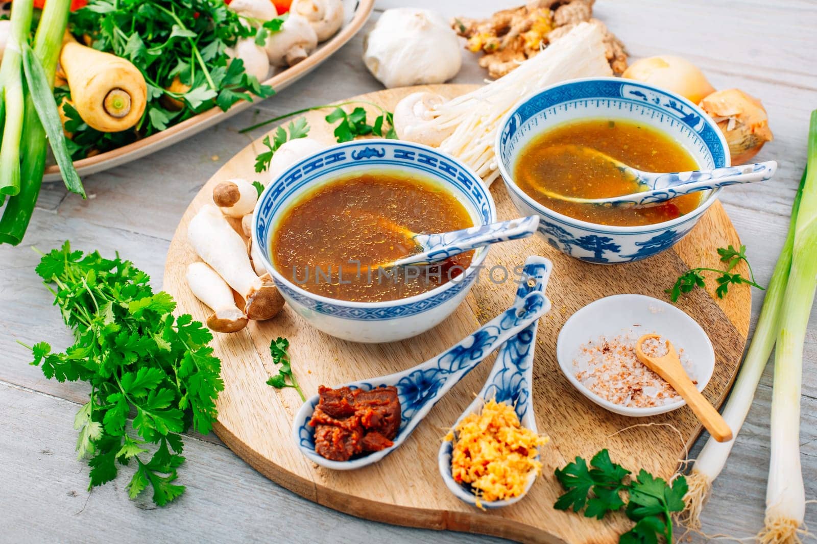 Miso, ramen or vegetable broth with ingredients on wooden background