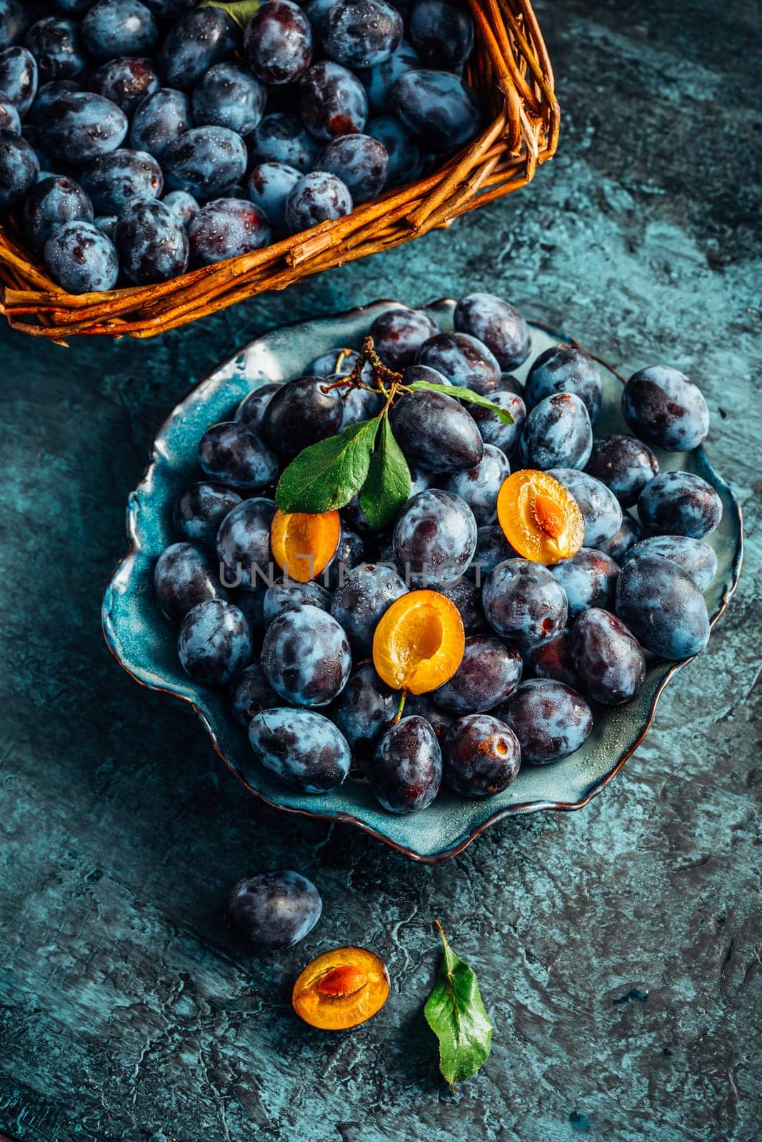 Freshly picked plums in a bowl and basket. Organic food and harvesting concept