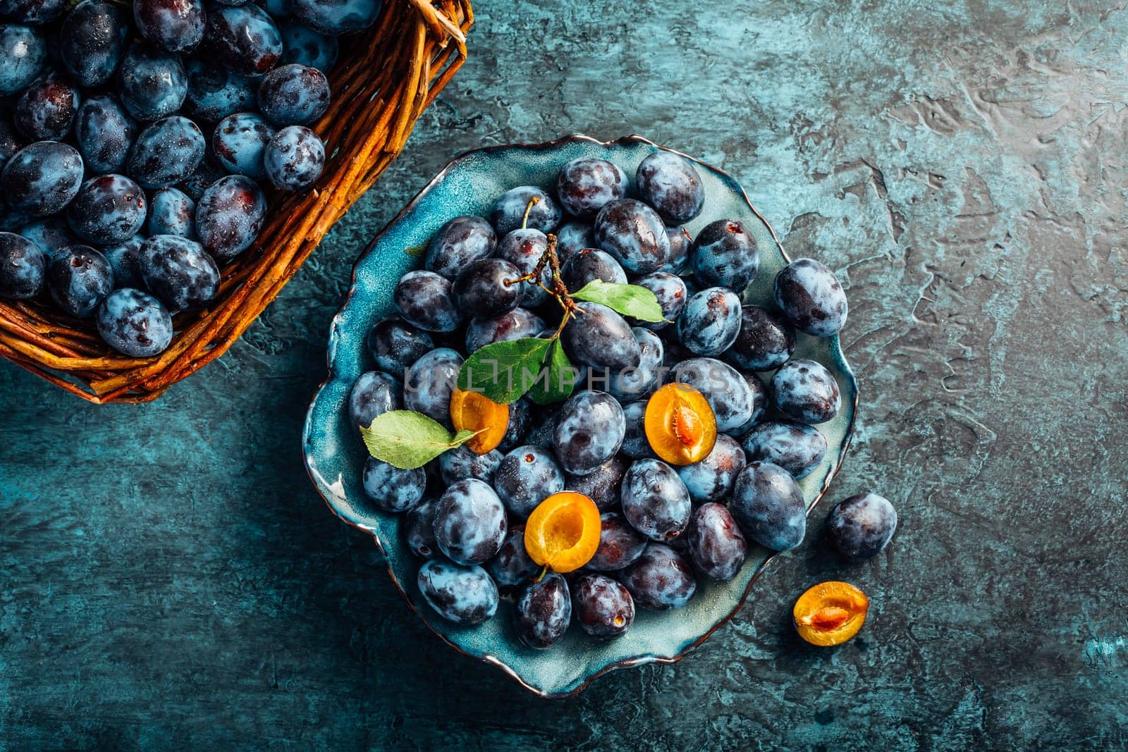 Freshly picked plums in a bowl and basket. Organic food and harvesting concept