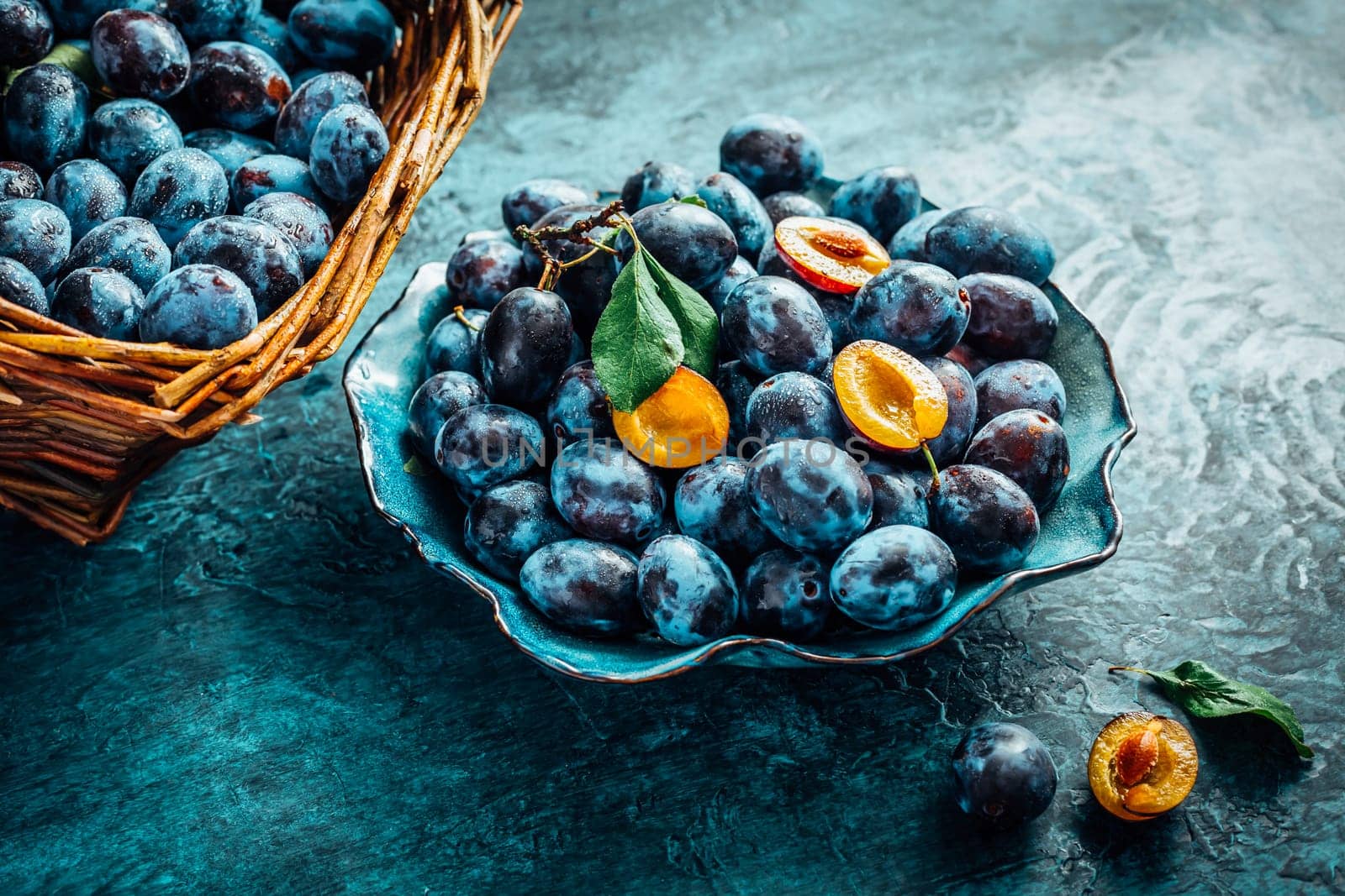 Freshly picked plums in a bowl and basket. Organic food and harvesting concept