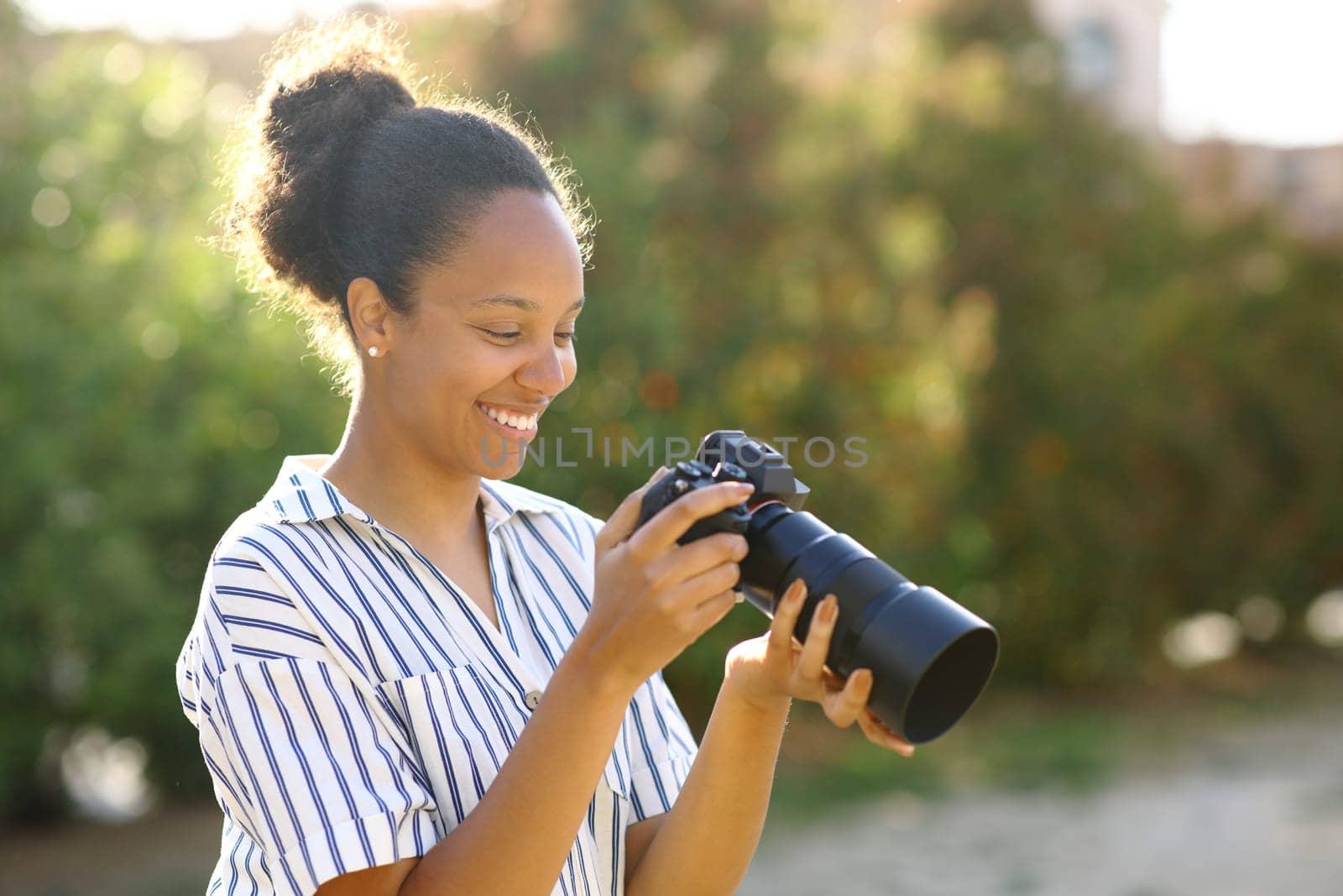 Happy photographer checking mirrorless camera in a park