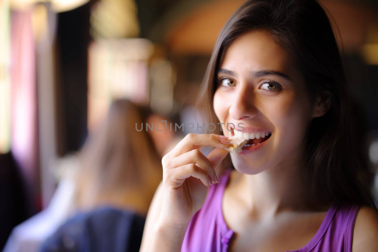 Happy beautiful restaurant customer eating bread looking at you
