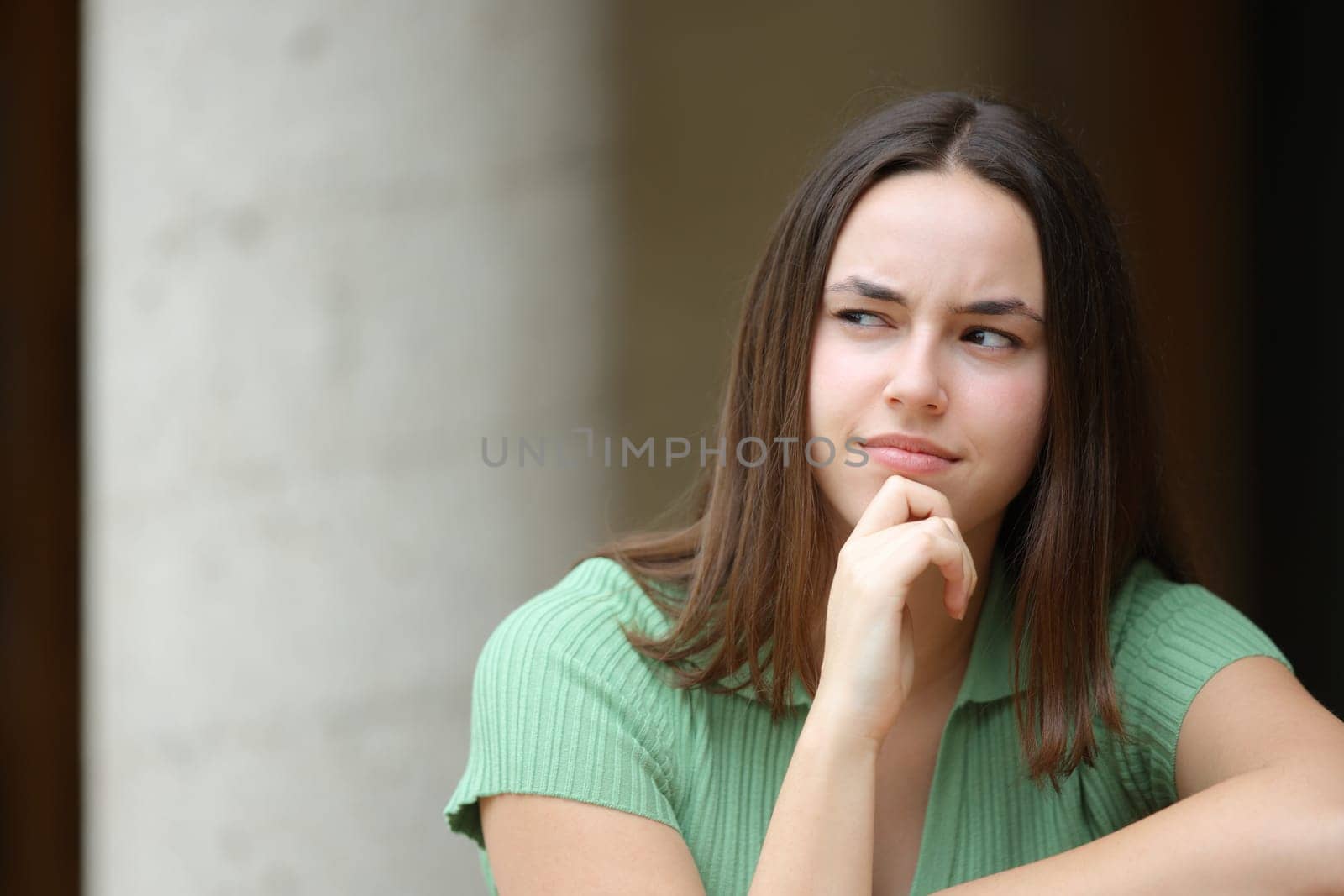 Front view portrait of a pensive woman in the street looks at side