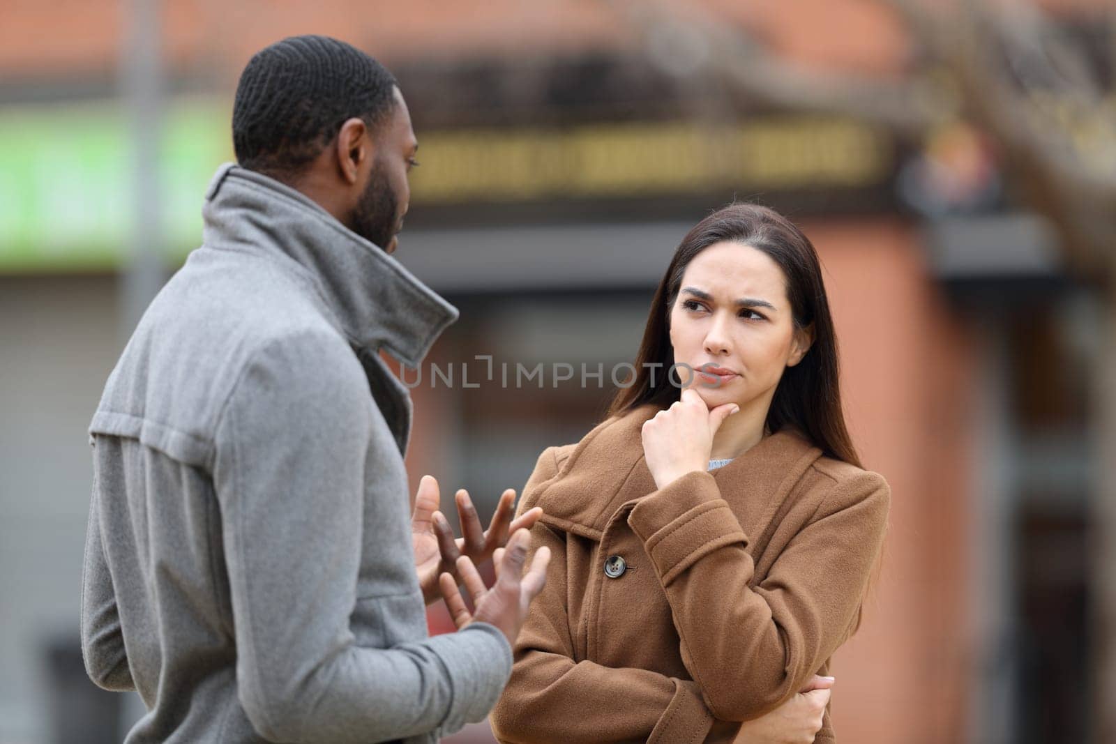 Suspicious woman listening a man talking in winter in the street