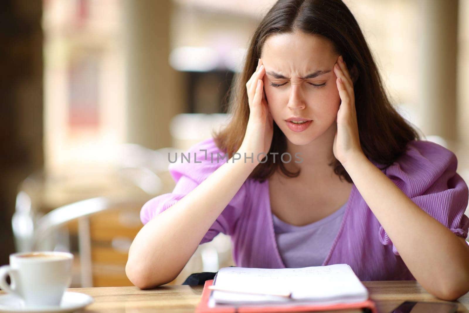 Student studying and suffering migraine in a bar terrace