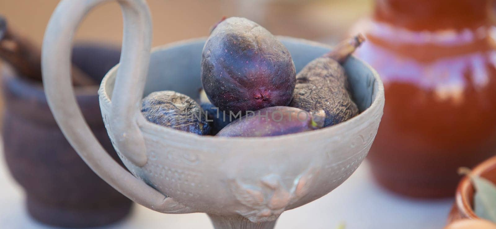 Clay cup full of mature figs. Ancient roman gastronomy concept