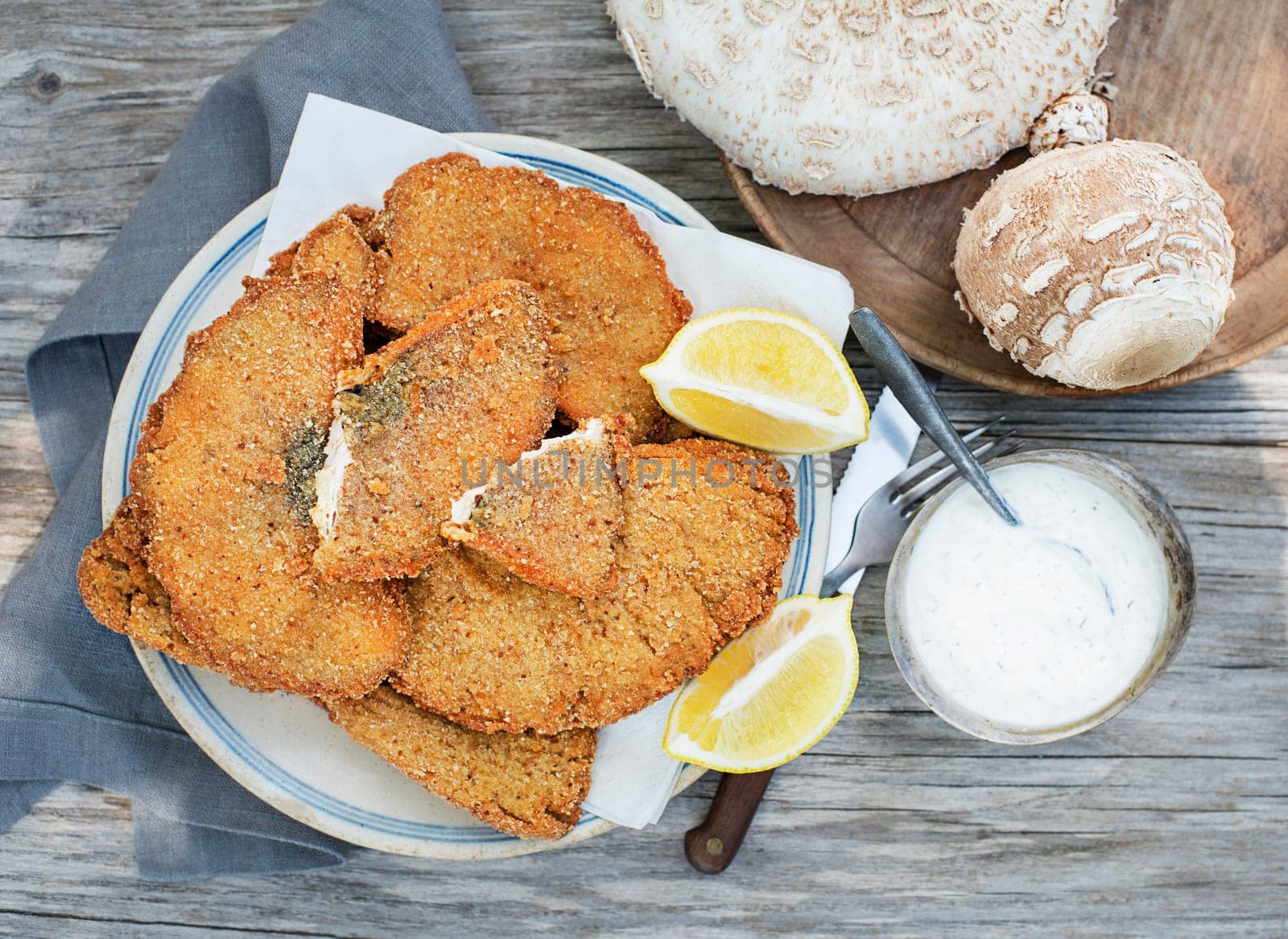 Macrolepiota procera parasol mushrooms breaded and crispy fried served on plate.