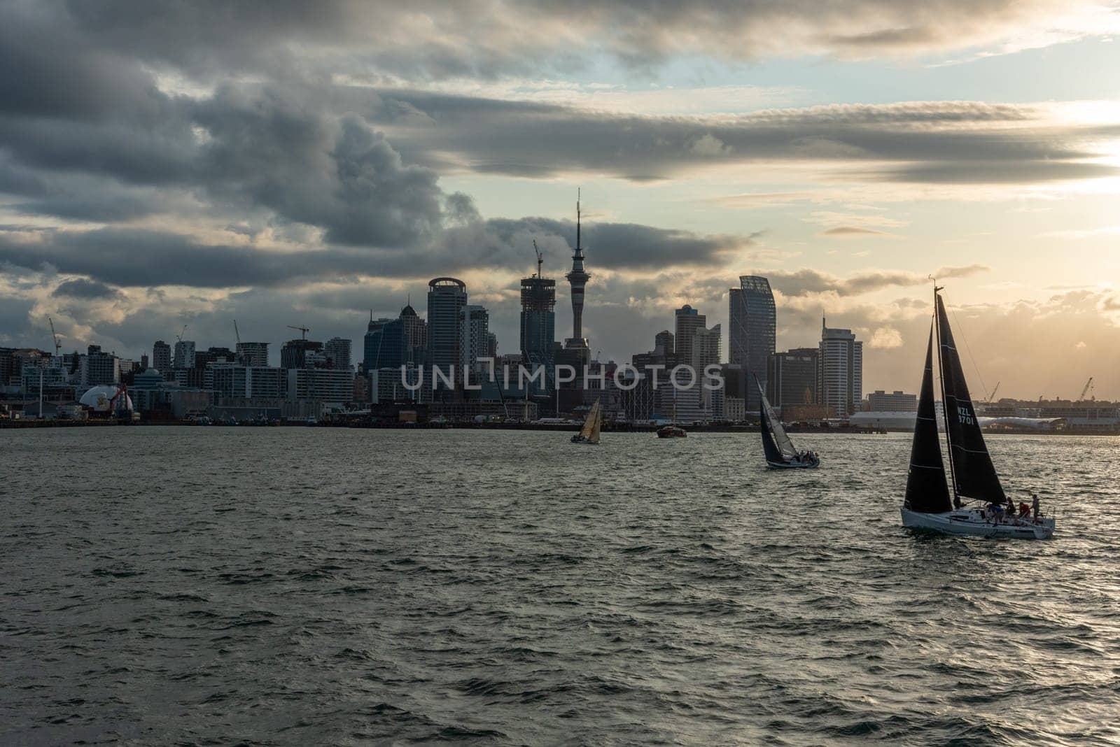 Famous skyline of Auckland Central Business District during sunset, people anjoying the warm summer evening on their sailboats, New Zealand