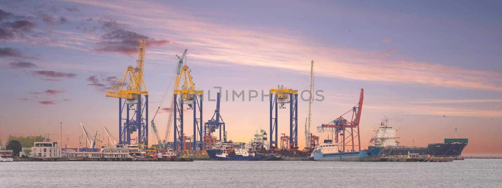 Beautiful sunrise over Haydarpasa Port, Istanbul, Turkey, with cargo ships and cranes silhouetted against the sky. Water reflects the colors of the sunrise, creating a vibrant and energetic scene
