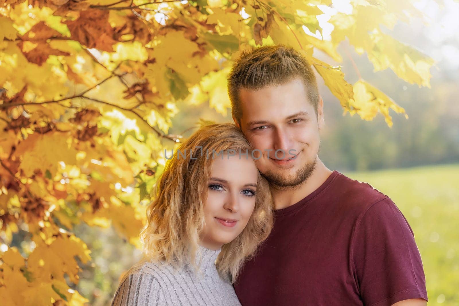 Young loving couple is posing in the autumn park. Horizontally.