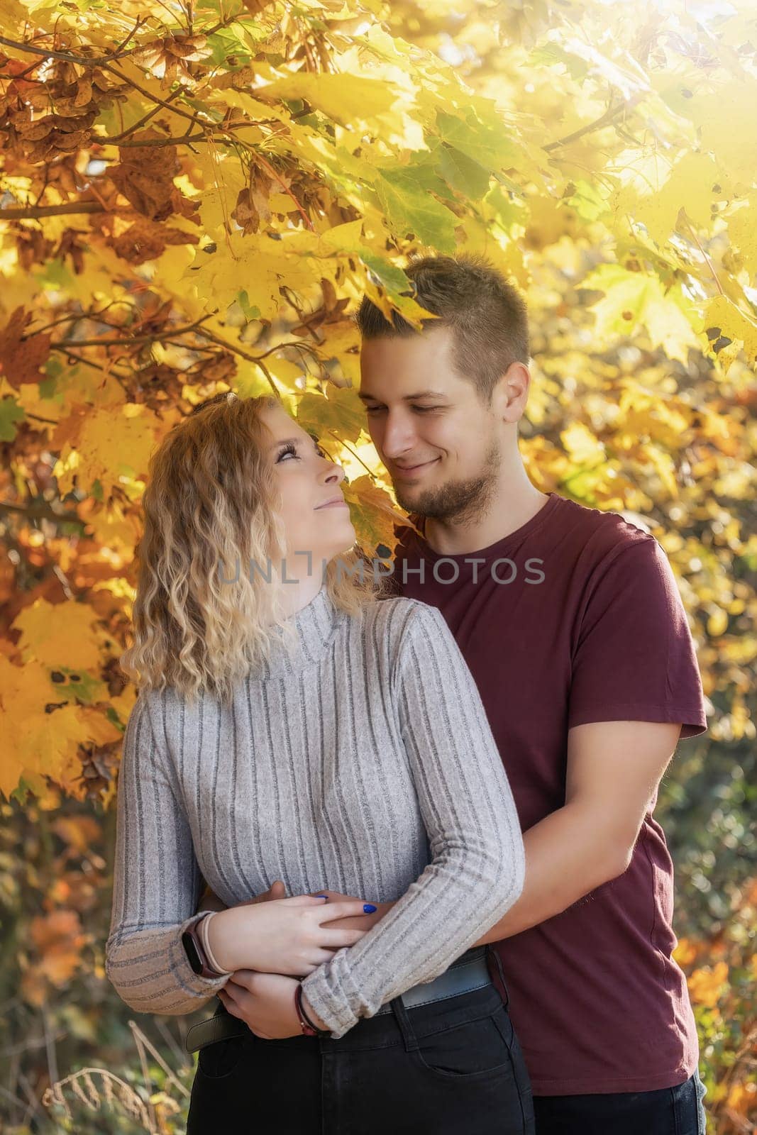 Young couple is hugging in autumn park. Vertically.