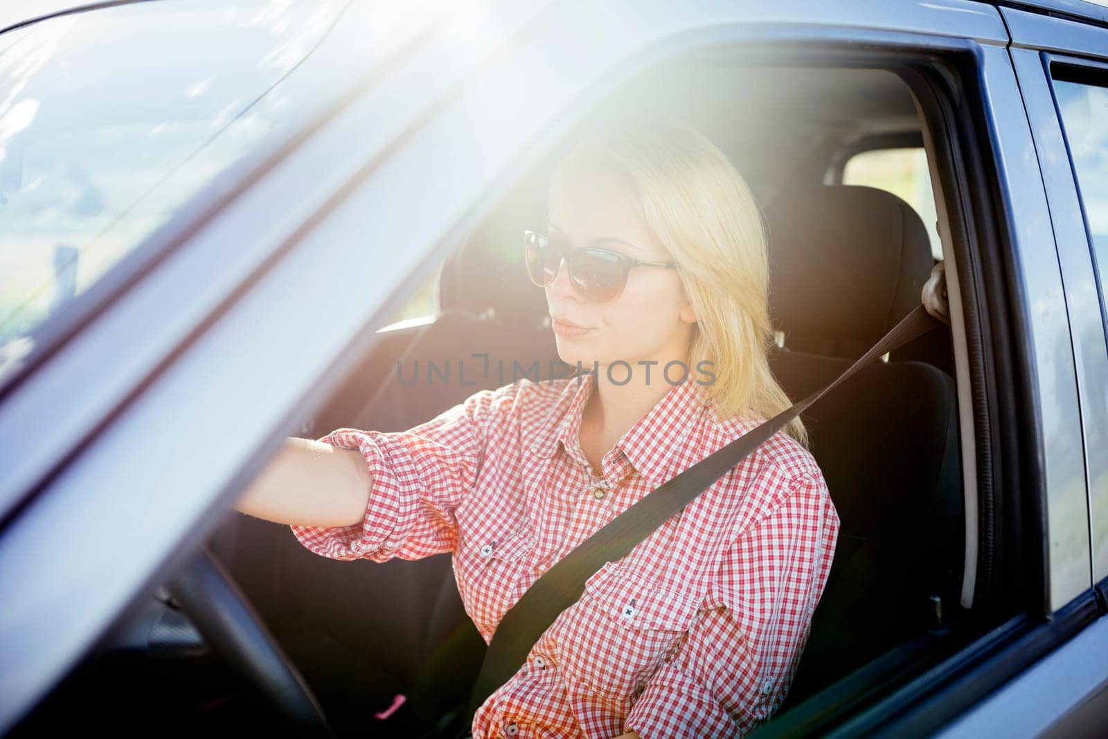 Happy young woman driver driving her new luxury car. Summer roadtrip travel and people lifestyle concept.