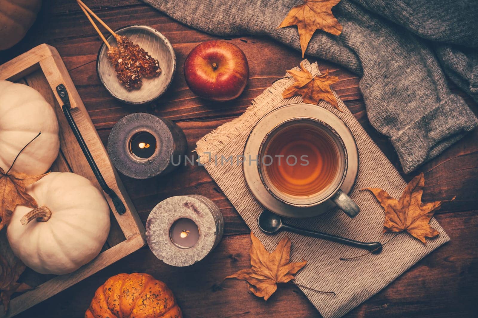 Autumn mood concept. Warm, cozy and rustic still life with cup of tea, candle and pumpkins.