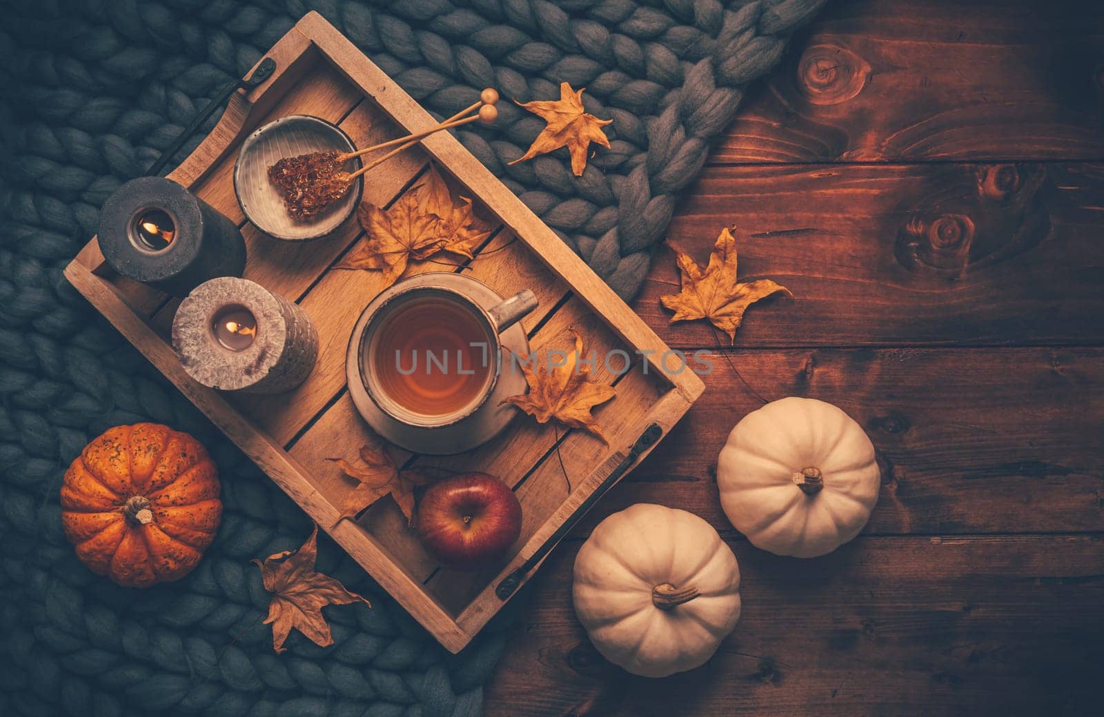 Autumn mood concept. Warm, cozy and rustic still life with cup of tea, candle and pumpkins.