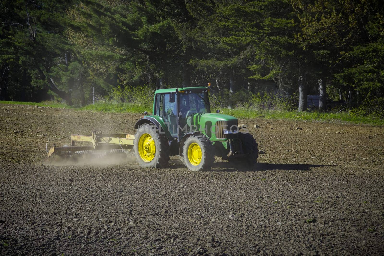 A serene rural landscape captured as a tractor effortlessly plows through a vast field, harmonizing nature and agriculture.