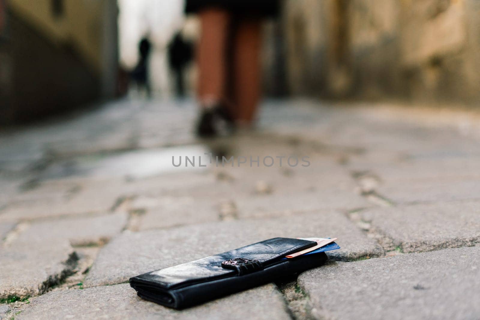 Photo of the sidewalk and legs of man who lost a black leather wallet while walking