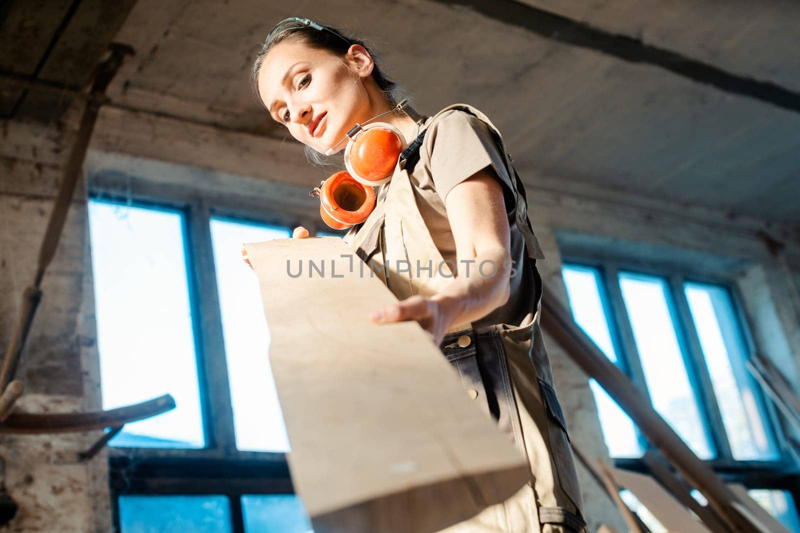 Beautiful woman carpenter checking quality of a plank for the next project