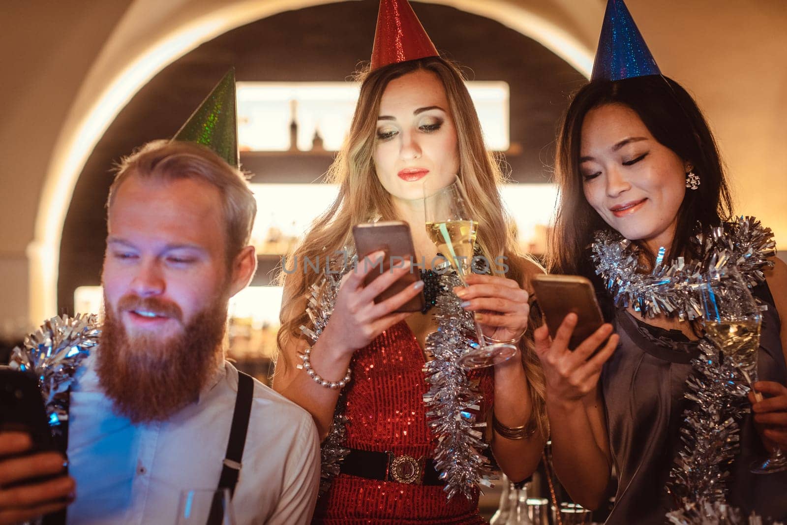 Group of young diverse people looking at their smartphones in the party