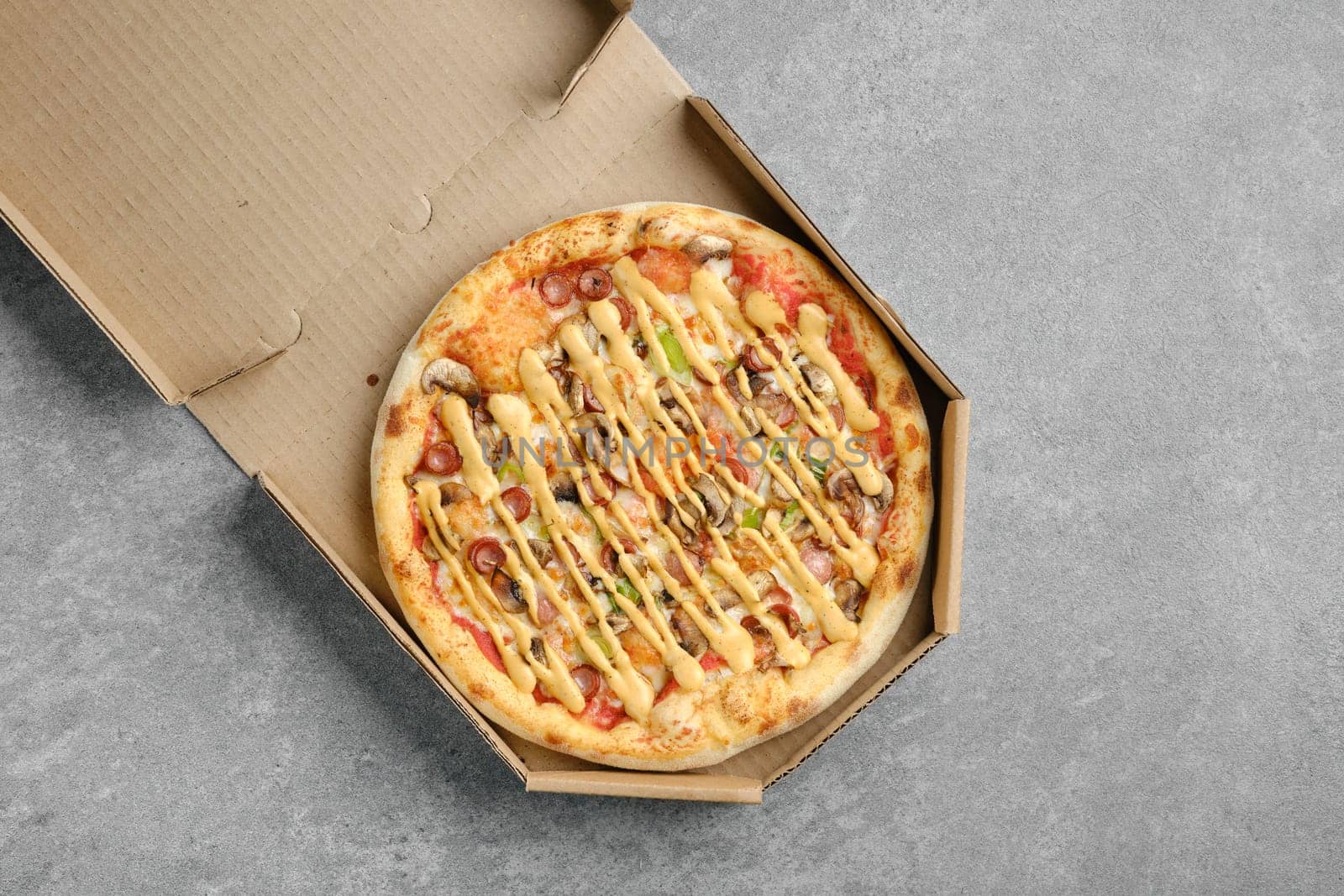Top view of pizza with thin sausage, jalapeno and champignon in cardboard box