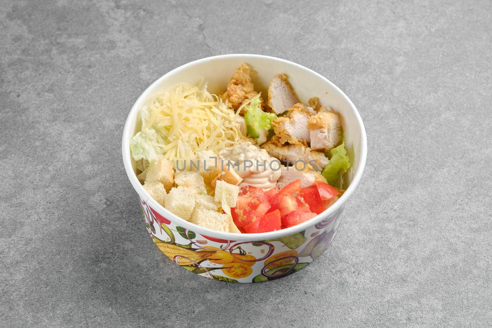 Salad with chicken meat, cheese, tomatoes, iceberg lettuce and crouton in cardboard bowl