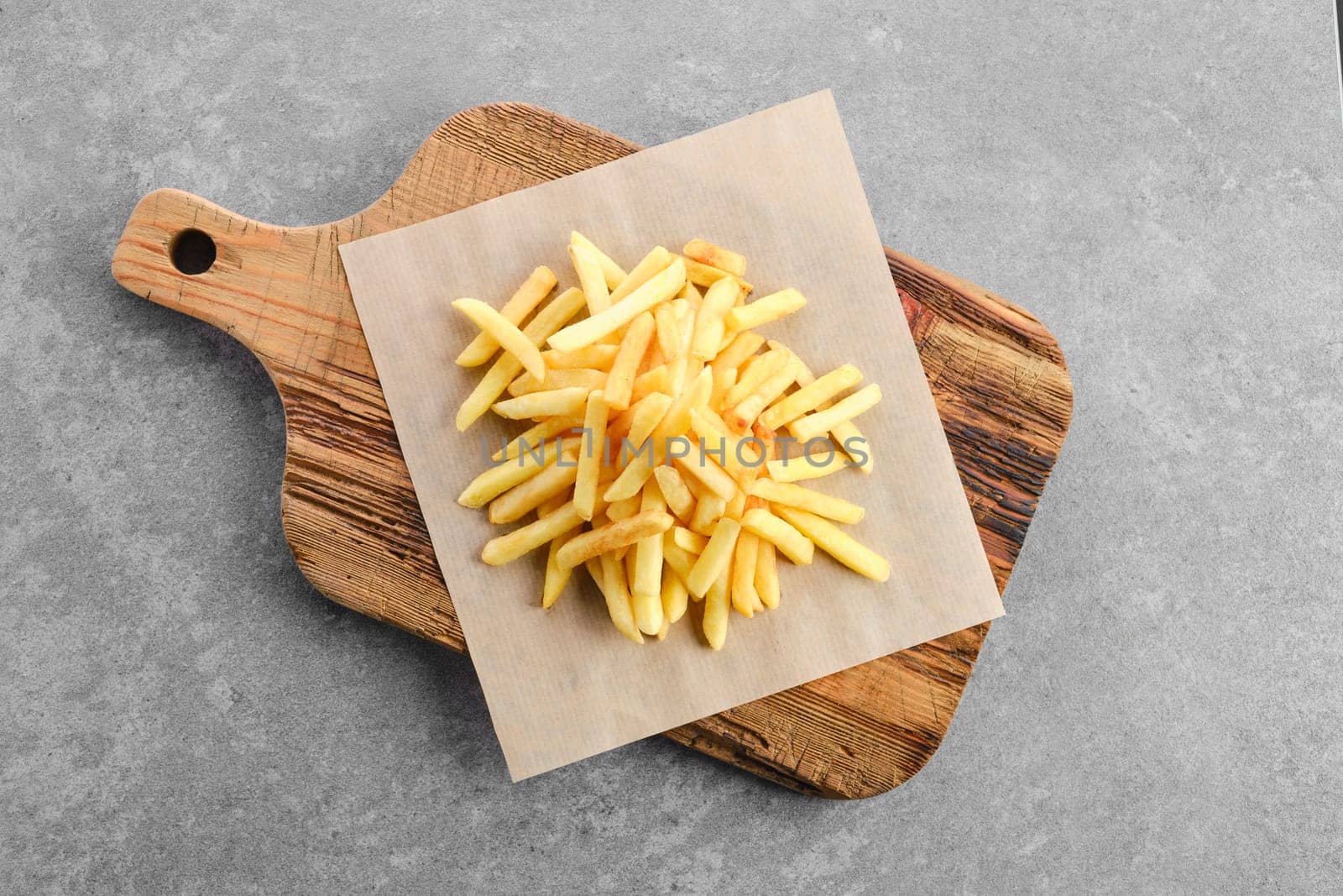 Top view of portion of salty french fries on paper