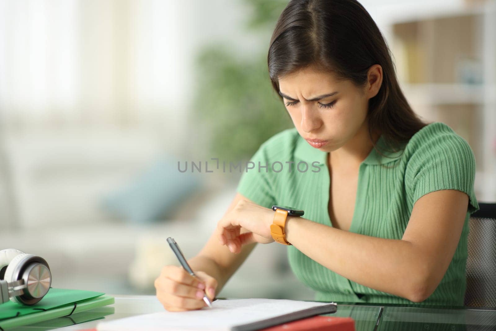 Frustated student checking smartwatch studying at home