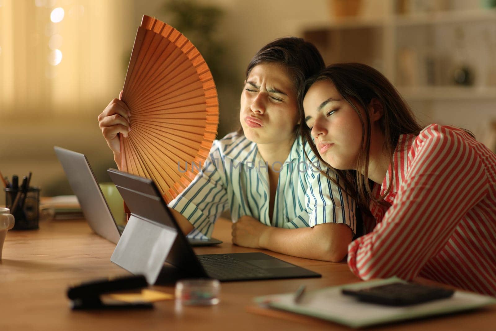 Stressed teleworkers fanning suffering heat stroke working at home in the night