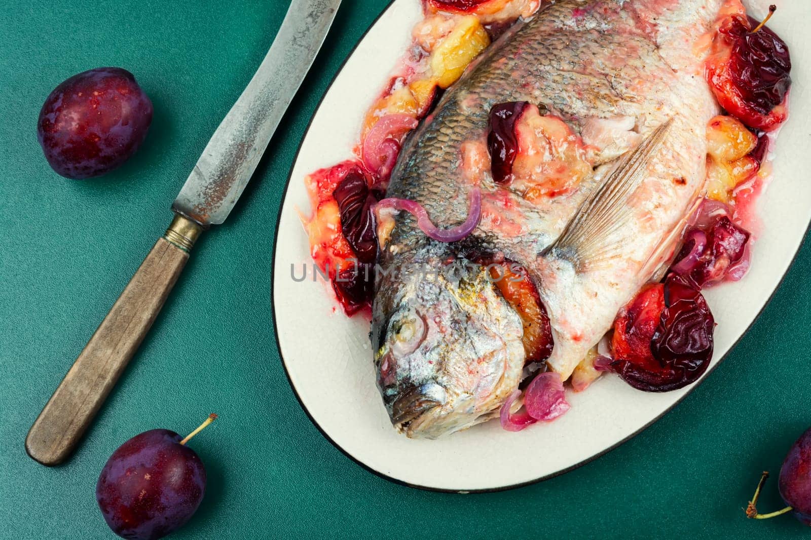 Dorado or sea bream fish baked with plums.