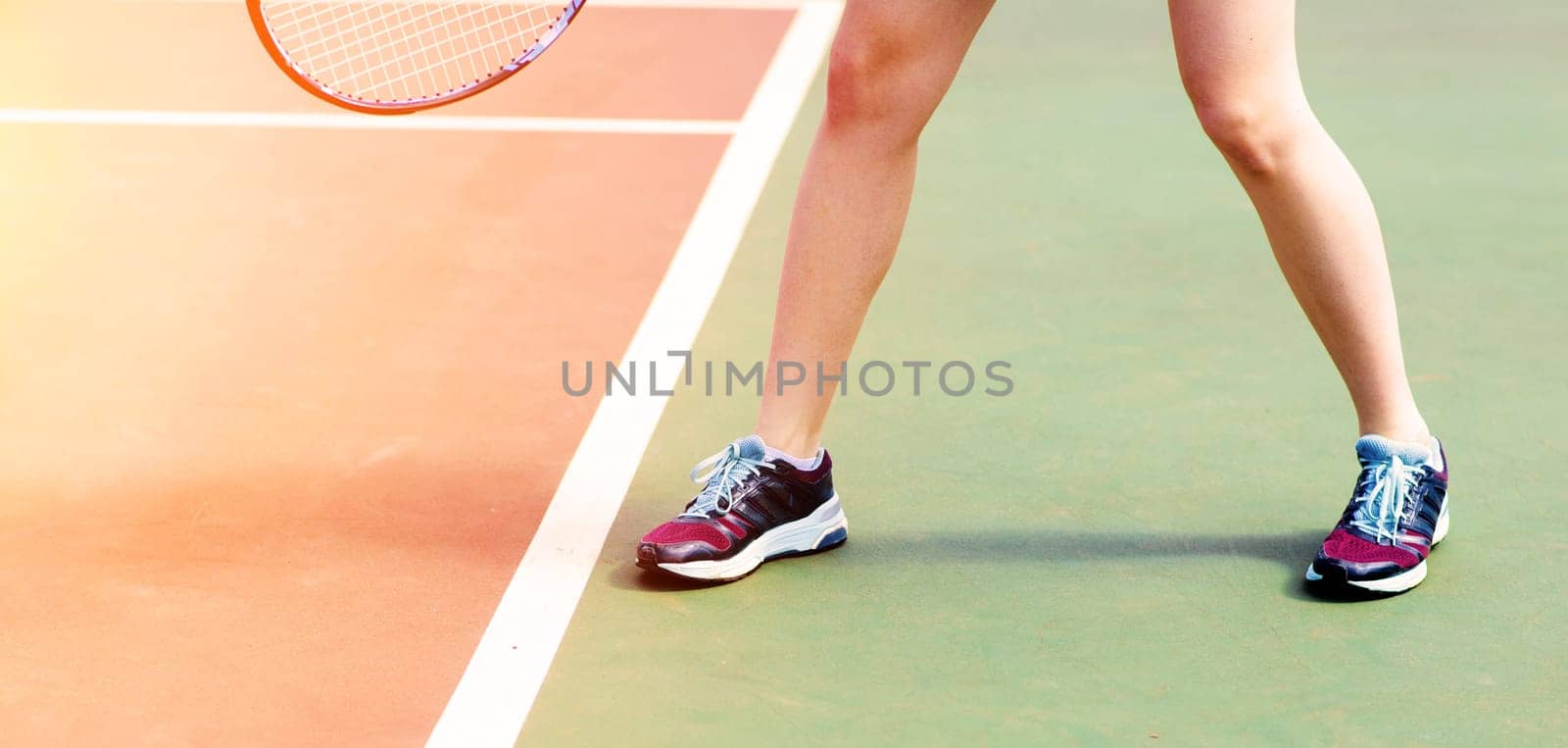 Legs of young girl in a closed tennis court with racket