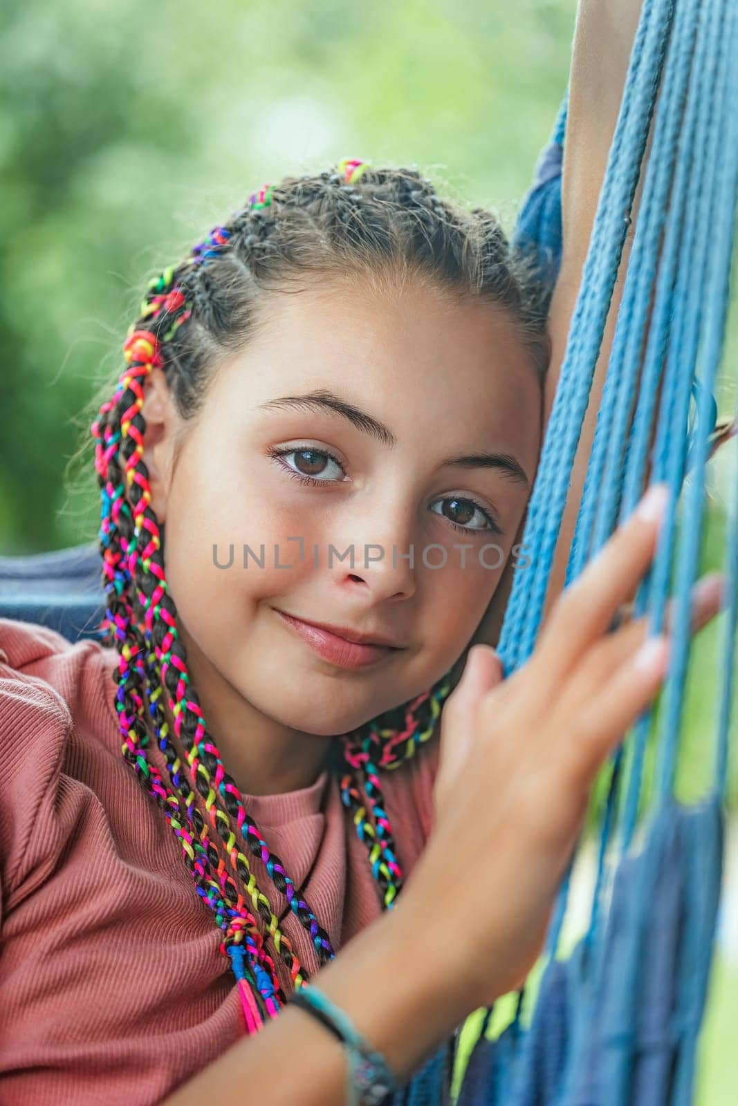 Closeup portrait of young girl with colorful braids in her hair smiling at the camera closeup.  Vertically.