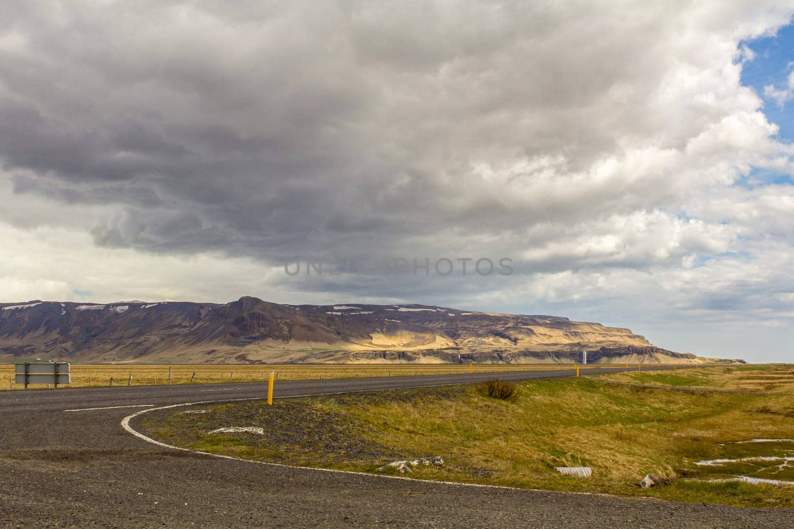 Road to Seljalandsfoss waterfall, the waterfall small in the background, Iceland