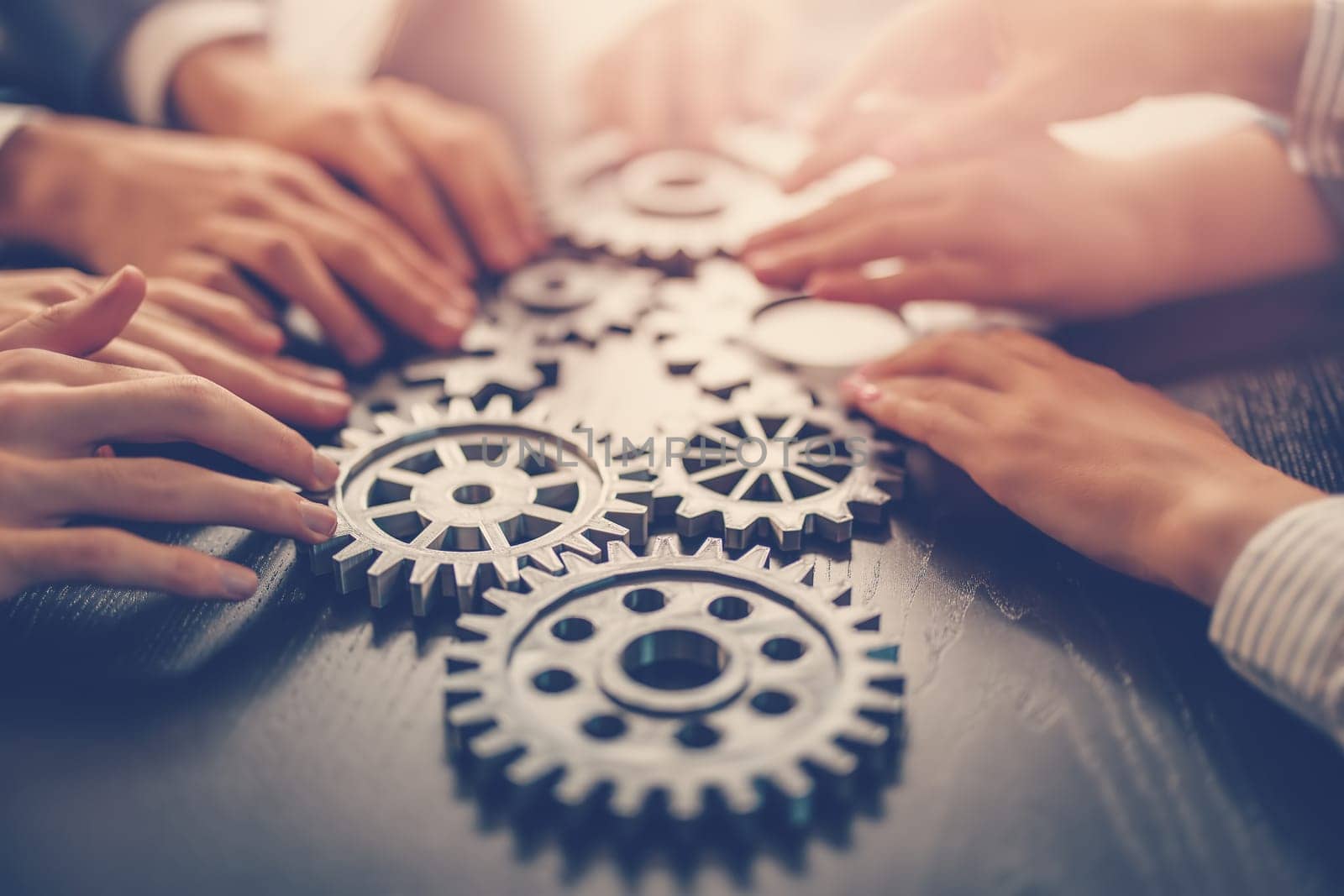 People joining cog wheel on the black desk. Concept of the teamwork, partnership and cooperation.