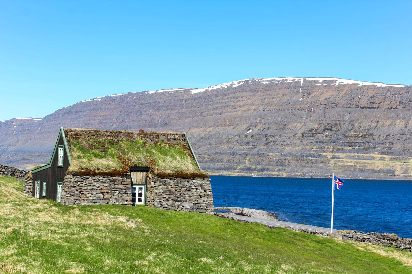 Icelandic flag in front of a romantic turf house, Iceland