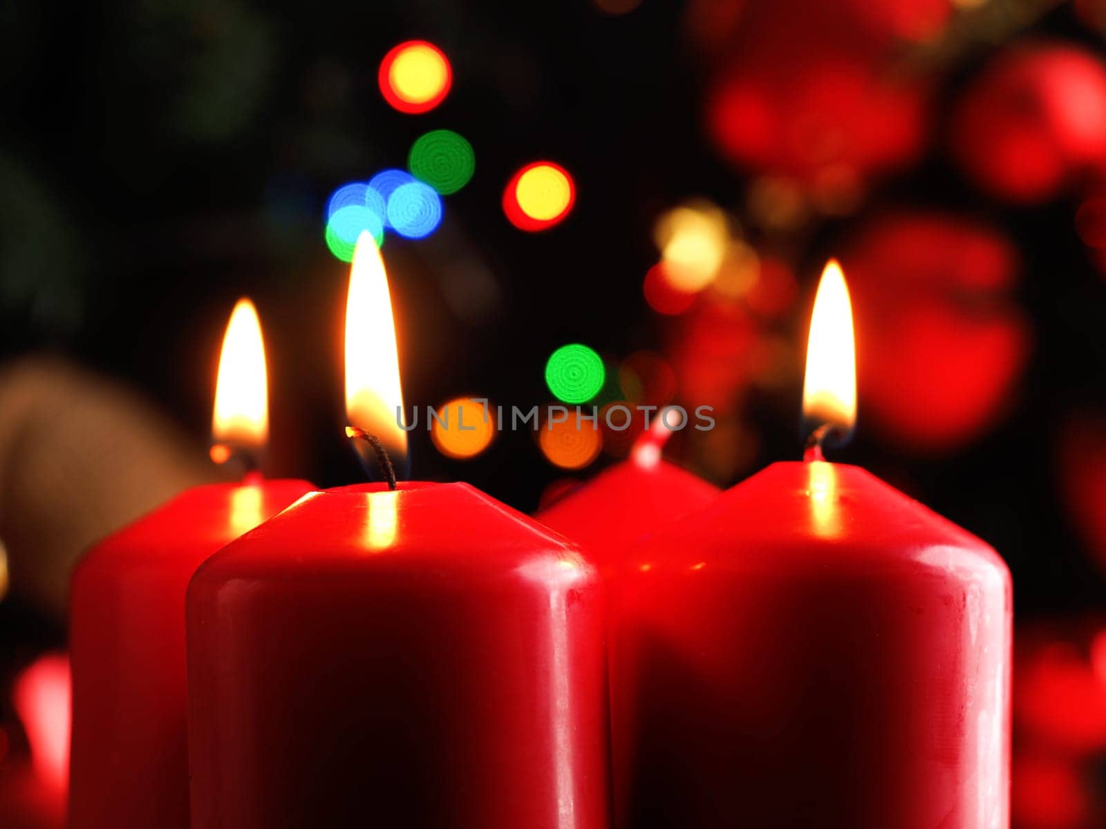 Third Advent candle burning, red Advent candles with decoration in a dark room, space for text or image