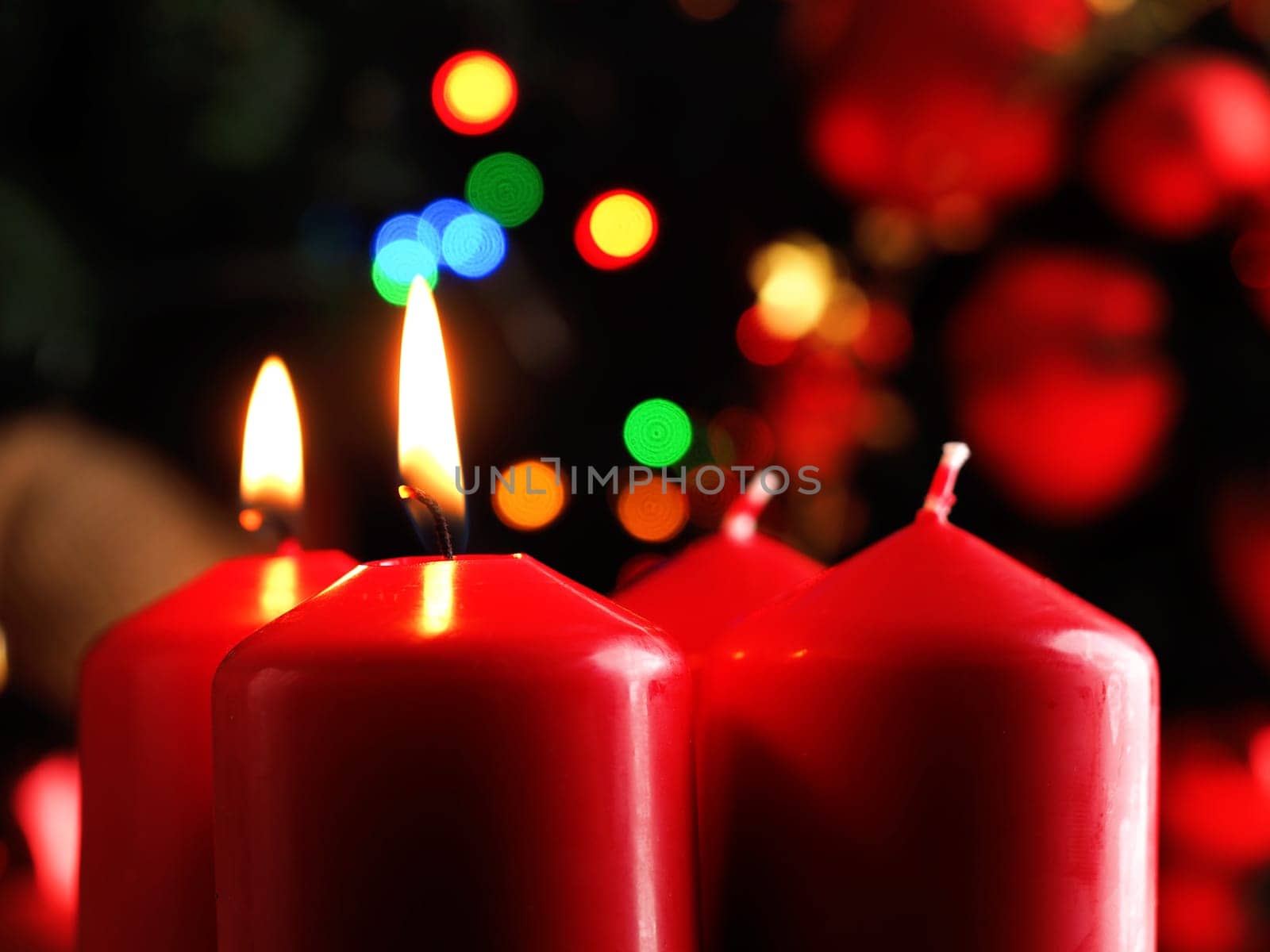 Second Advent candle burning, red Advent candles with decoration in a dark room, space for text or image