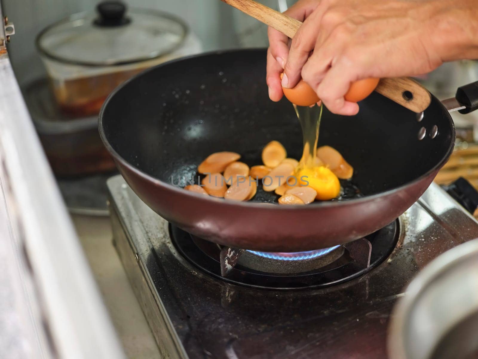 Cooking of sausage fried rice and crack an egg with mixed vegetable .