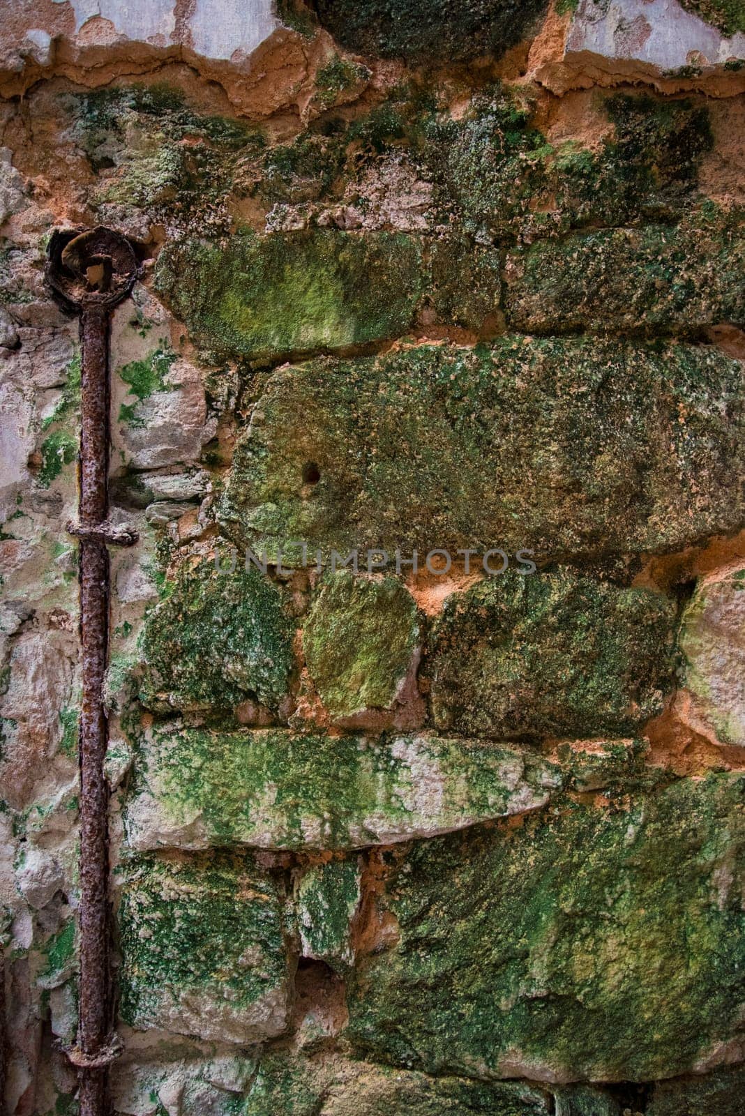 Old stone wall with a rusty heating pipe and a know, USA