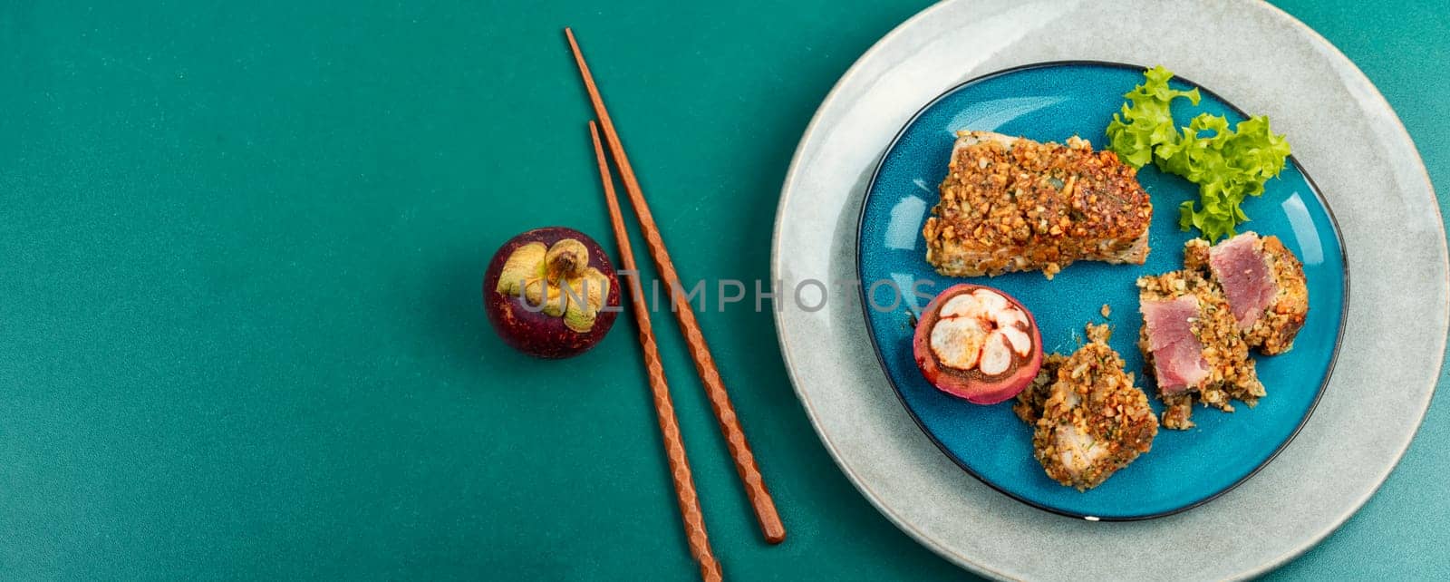 Steak of baked tuna fillet in a nut panic with a mangosteens. Space for text. Long banner.