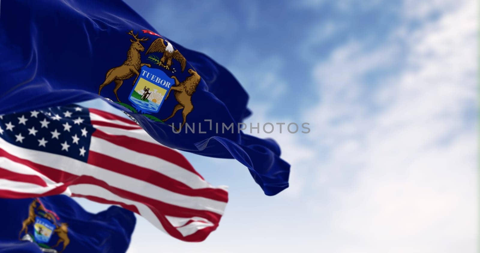 Flags of Michigan and the United States waving in the wind on a clear day. Patriotism and identity concept. 3d illustration render. Rippled fabric. Selective focus