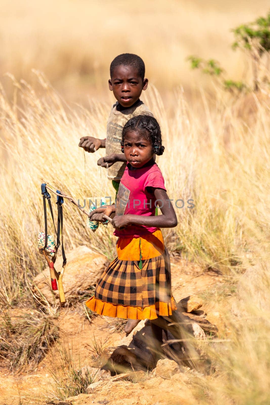 Andringitra Mountains, Madagascar - November 15th 2022: Local young girl and boy selling souvenirs standing in mountainous landscape. Andringitra, Madagascar
