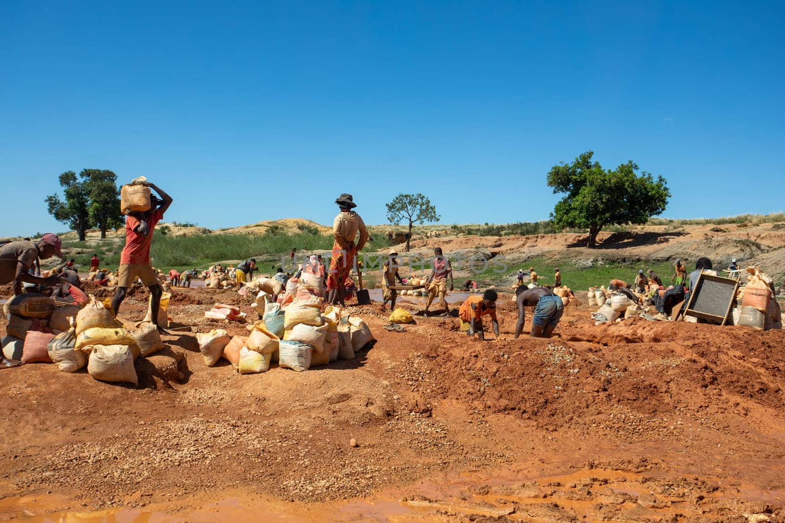 Ihosy, Ilakaka, Madagascar - November 20, 2022: Local people mine for gems and pan for gold in a river. The town is a major center of sapphire production and trade.