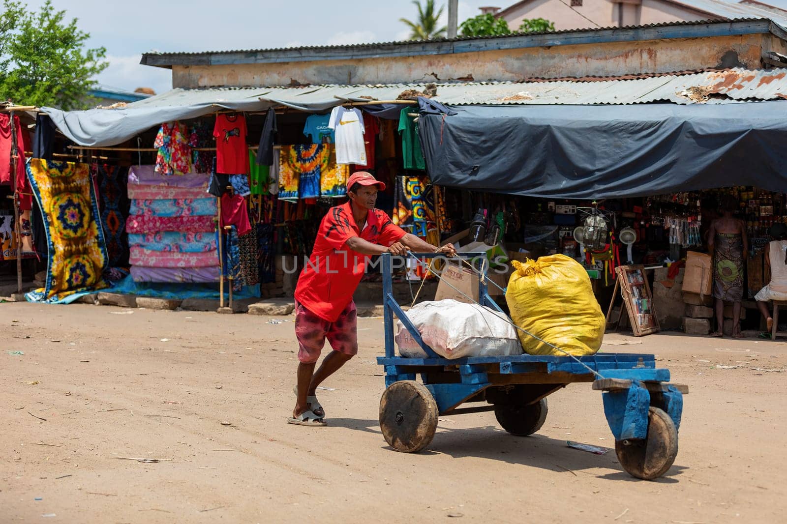 Miandrivazo, Madagascar - November 2nd 2022: A man engaged in transporting bags pushes a primitive cart on the streets of Miandrivazo.