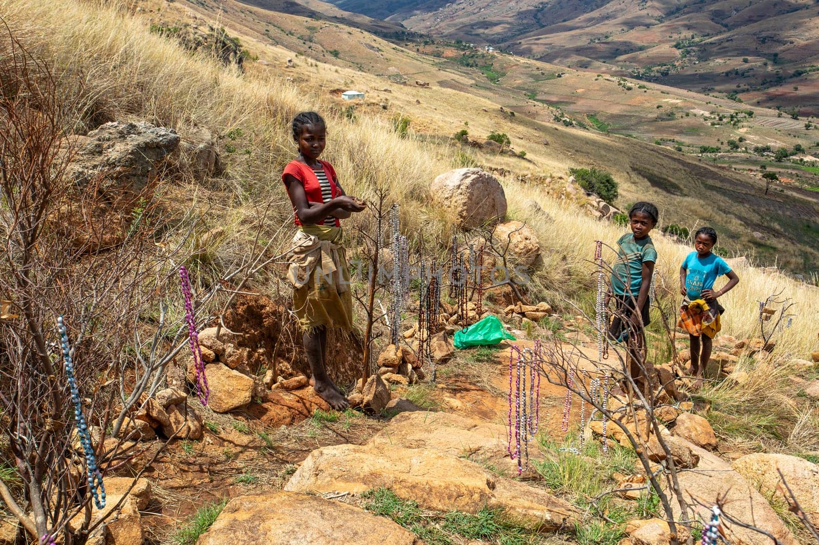 Andringitra Mountains, Madagascar - November 15th 2022: Local young girl and boy selling souvenirs standing in mountainous landscape. Andringitra, Madagascar